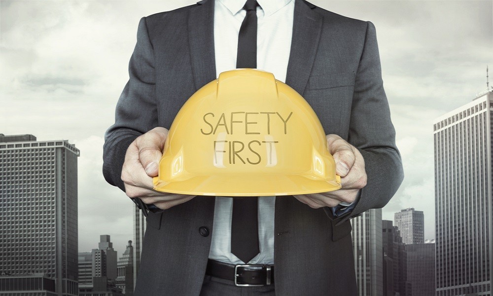 Safety first text on helmet what businessman is holding How To Stay Safe At Work - People Development Magazine